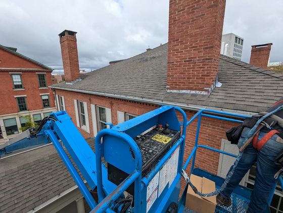 Mr. Gutter crew working from a lift on a brick building