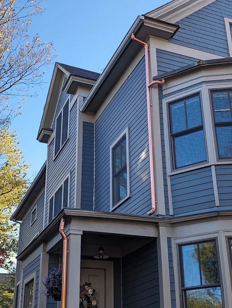 Copper gutters and downspouts on a blue two-family house